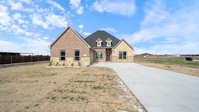 view of front facade with stone siding, brick siding, and fence