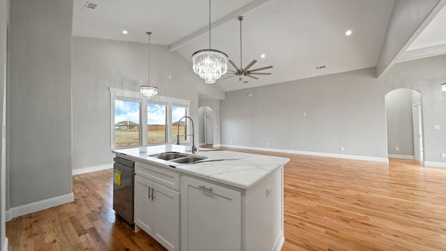 kitchen featuring stainless steel dishwasher, arched walkways, a sink, and beamed ceiling