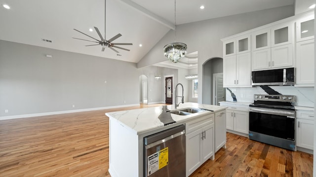 kitchen with visible vents, arched walkways, light wood-style flooring, stainless steel appliances, and a sink