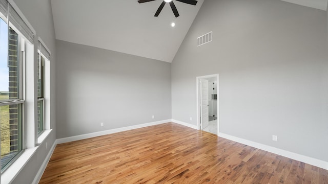 unfurnished room with visible vents, ceiling fan, wood finished floors, high vaulted ceiling, and baseboards