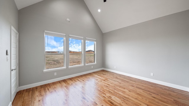 spare room with light wood finished floors, baseboards, high vaulted ceiling, and recessed lighting