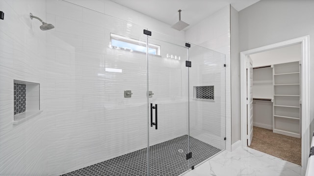 bathroom with marble finish floor, a shower stall, a spacious closet, and baseboards