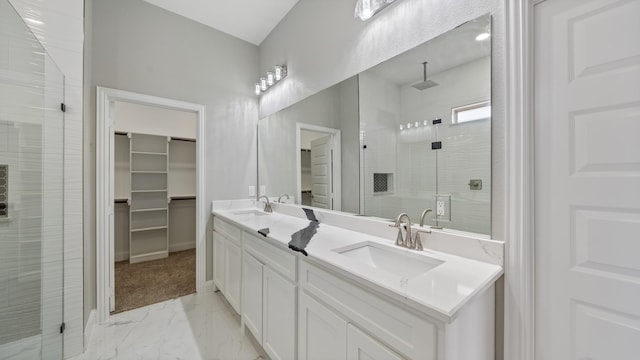 bathroom with a walk in closet, marble finish floor, double vanity, a stall shower, and a sink