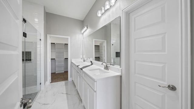 full bathroom with a sink, marble finish floor, double vanity, a stall shower, and a walk in closet