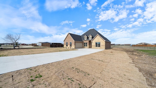 view of front of property with stone siding, concrete driveway, fence, and an attached garage