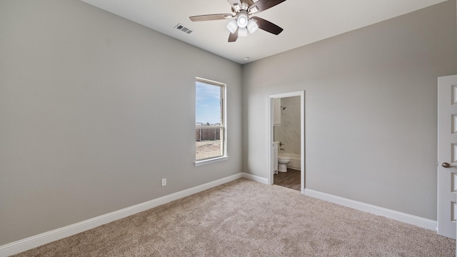 unfurnished bedroom featuring baseboards, visible vents, ensuite bath, ceiling fan, and carpet flooring