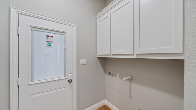 laundry area with wood finished floors, cabinet space, and baseboards