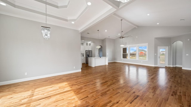 unfurnished living room featuring arched walkways, beam ceiling, light wood-style flooring, baseboards, and ceiling fan with notable chandelier