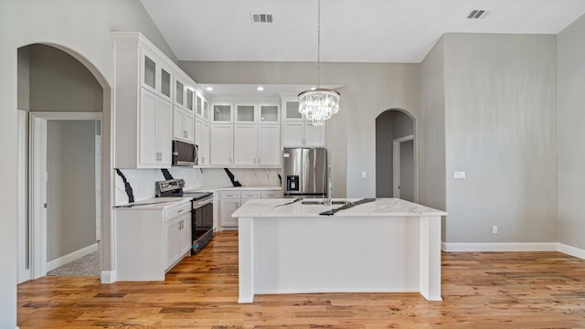 kitchen with arched walkways, visible vents, appliances with stainless steel finishes, light wood-style floors, and white cabinets