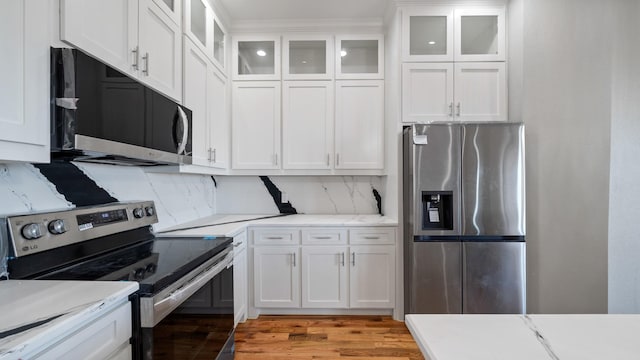 kitchen with stainless steel appliances, decorative backsplash, and white cabinets