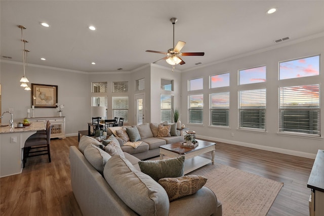 living area with recessed lighting, crown molding, baseboards, and wood finished floors