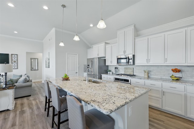 kitchen with a breakfast bar area, stainless steel appliances, backsplash, a sink, and an island with sink