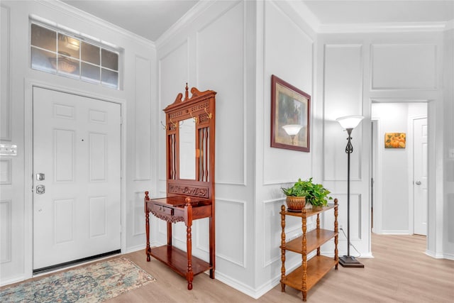 foyer featuring ornamental molding, light wood-style floors, and a decorative wall