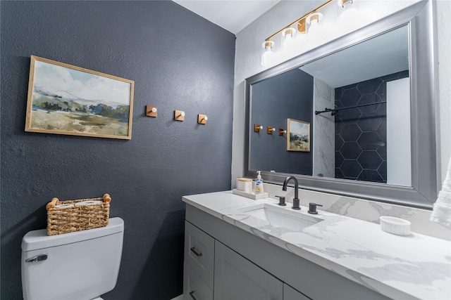 bathroom with a textured wall, vanity, walk in shower, and toilet