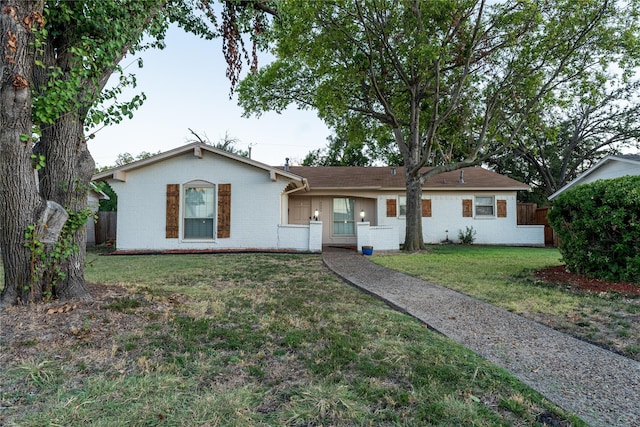 ranch-style house featuring brick siding, fence, and a front lawn