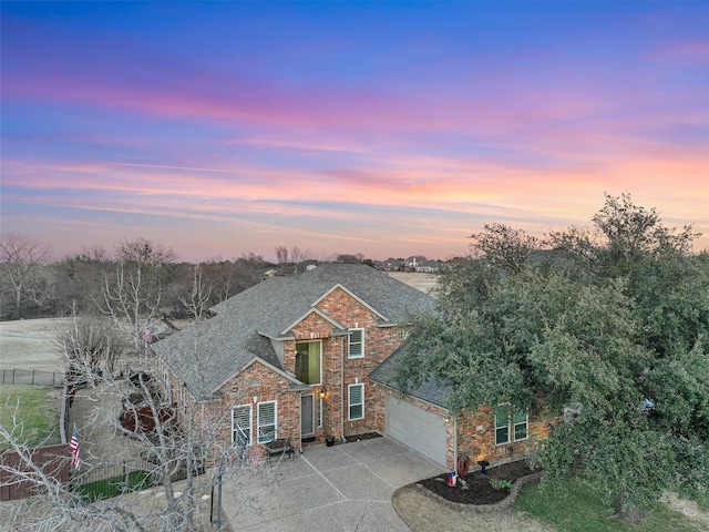 view of front of property with a garage, brick siding, fence, driveway, and roof with shingles