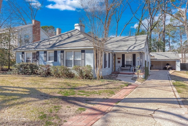 view of front of property with an attached carport, covered porch, brick siding, concrete driveway, and a front yard