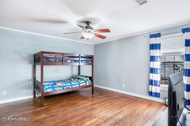 bedroom with baseboards, visible vents, wood finished floors, and ornamental molding