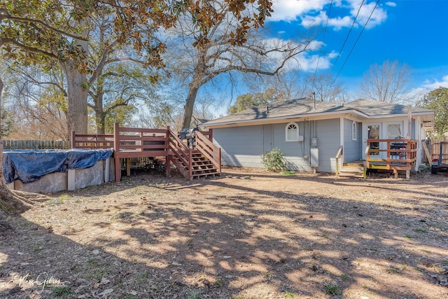 back of property with a covered pool and a wooden deck