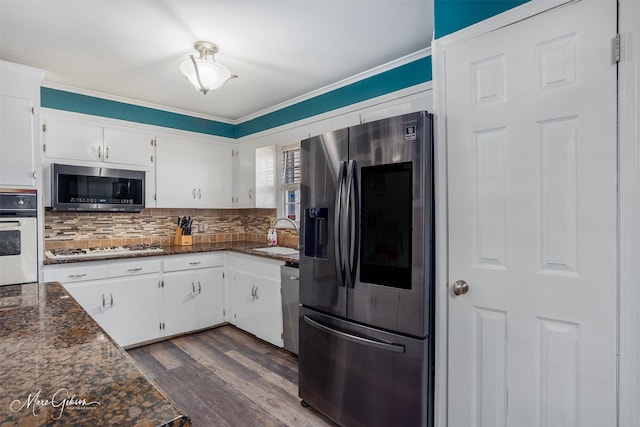 kitchen featuring white cabinets, dark wood finished floors, decorative backsplash, stainless steel appliances, and a sink