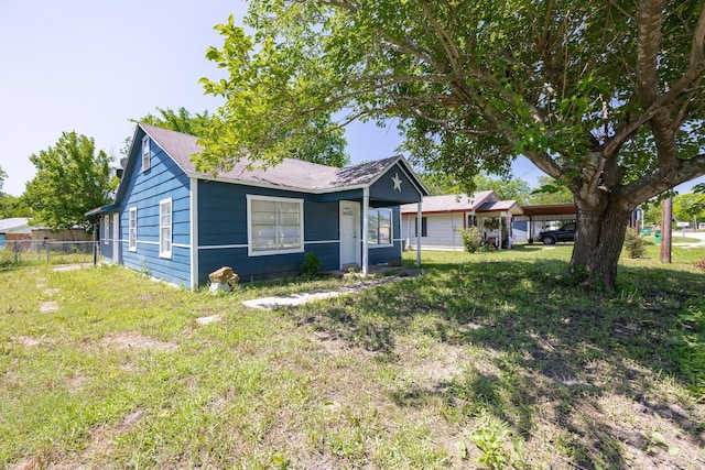 bungalow-style home with fence, an attached carport, and a front yard