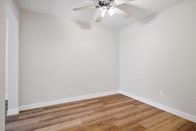 spare room with ceiling fan, light wood-type flooring, and baseboards