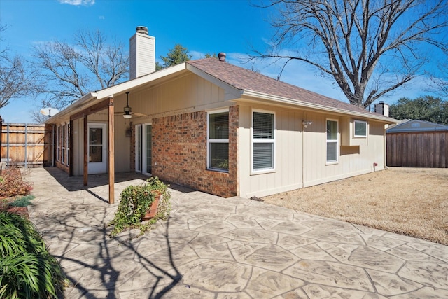 back of house featuring a patio, ceiling fan, a chimney, fence, and brick siding