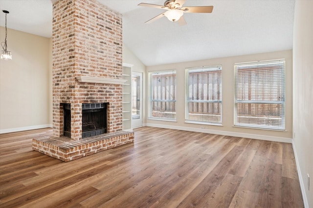 unfurnished living room with a ceiling fan, a brick fireplace, vaulted ceiling, wood finished floors, and baseboards