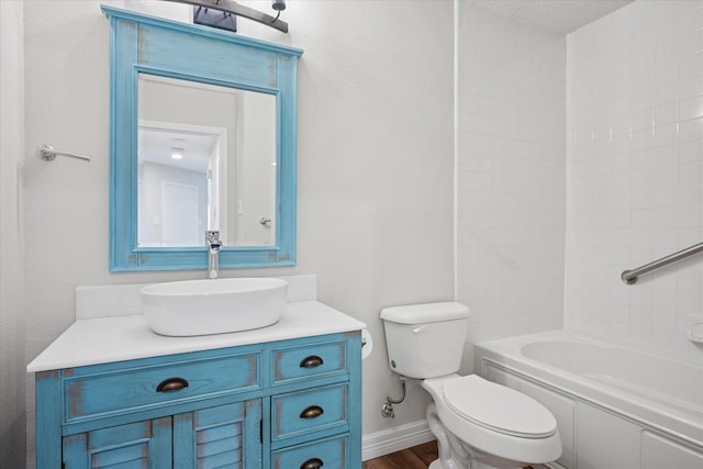 bathroom featuring baseboards, toilet, wood finished floors, vanity, and shower / bathing tub combination