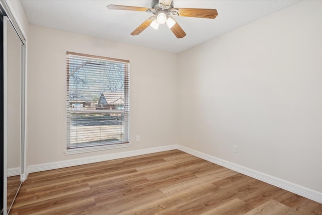 empty room featuring baseboards, ceiling fan, a textured ceiling, and light wood-style floors