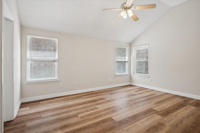 unfurnished room with lofted ceiling, ceiling fan, wood finished floors, and baseboards