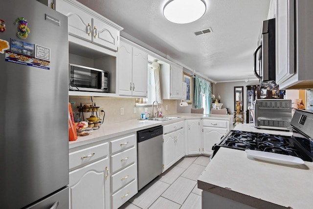 kitchen featuring stainless steel appliances, white cabinets, visible vents, and a sink