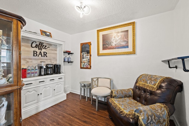 living area featuring dark wood-style floors, a textured ceiling, and baseboards