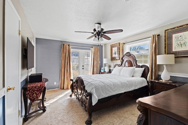 bedroom with ceiling fan, a textured ceiling, light carpet, access to exterior, and french doors