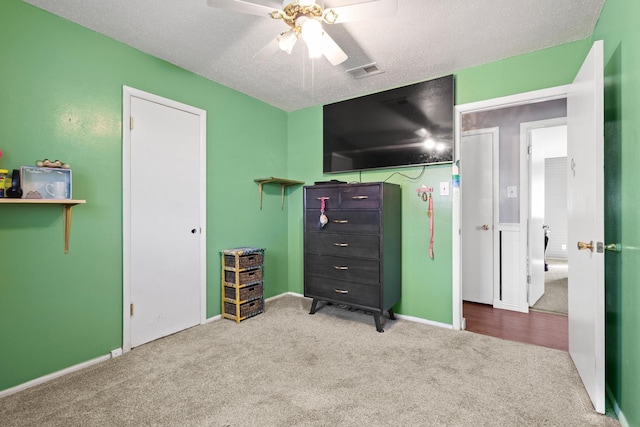 unfurnished bedroom with baseboards, visible vents, a ceiling fan, a textured ceiling, and carpet floors