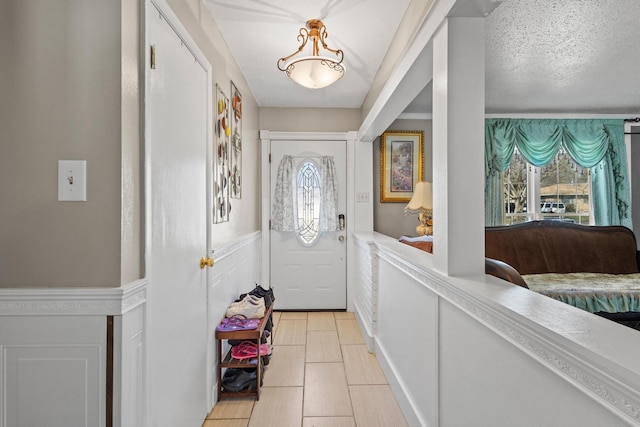 doorway to outside with wainscoting and a decorative wall