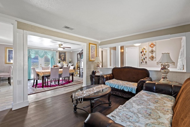 living area featuring crown molding, a textured ceiling, visible vents, and wood finished floors