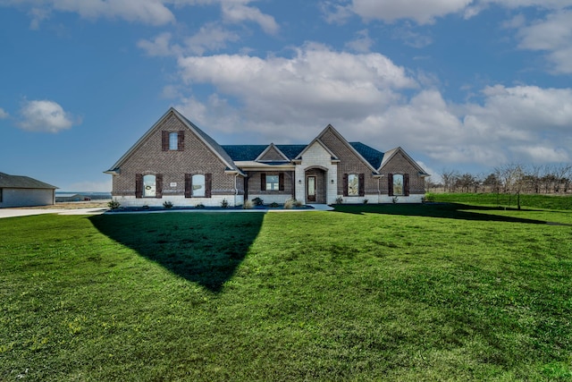 french country inspired facade with brick siding and a front yard