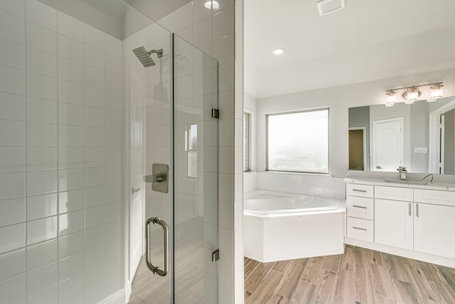 bathroom featuring visible vents, wood finished floors, vanity, a shower stall, and a bath