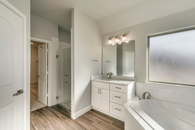 full bath with a stall shower, wood finish floors, a garden tub, and vanity