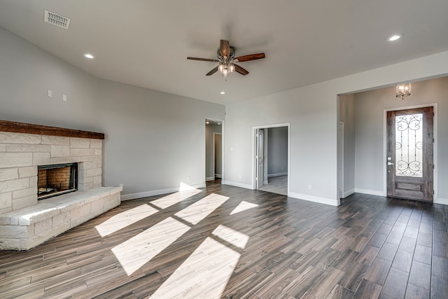 unfurnished living room featuring baseboards, visible vents, dark wood-style flooring, a fireplace, and ceiling fan with notable chandelier