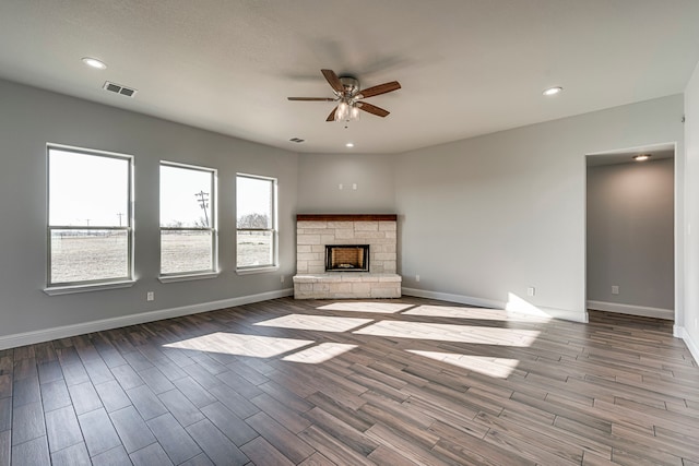 unfurnished living room featuring baseboards, visible vents, a ceiling fan, wood finished floors, and a fireplace