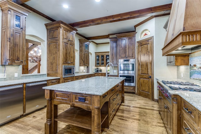 kitchen with light wood-style floors, appliances with stainless steel finishes, arched walkways, and crown molding