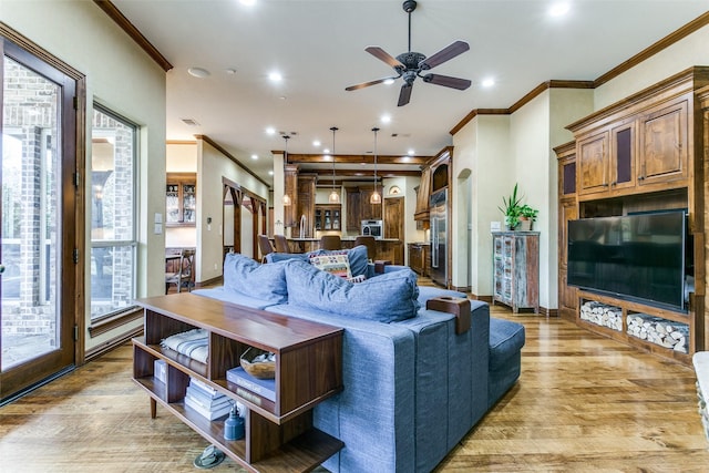 living room with a ceiling fan, recessed lighting, crown molding, and light wood finished floors