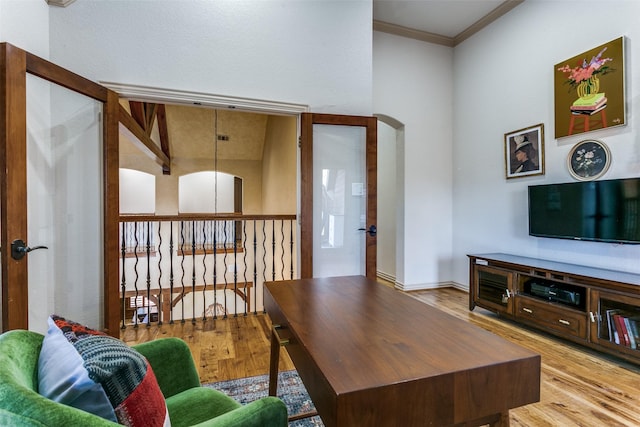 living area featuring arched walkways, wood finished floors, and crown molding