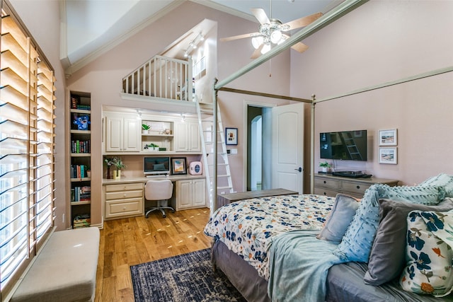 bedroom featuring high vaulted ceiling, a ceiling fan, light wood-style floors, ornamental molding, and built in desk