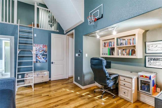 office space featuring baseboards, high vaulted ceiling, and light wood-style floors