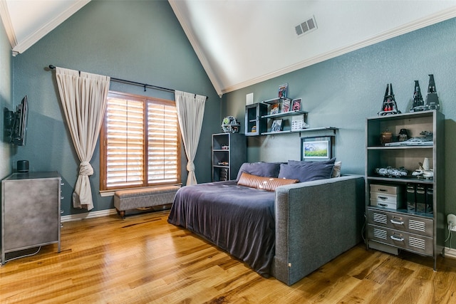 bedroom featuring high vaulted ceiling, wood finished floors, visible vents, baseboards, and ornamental molding