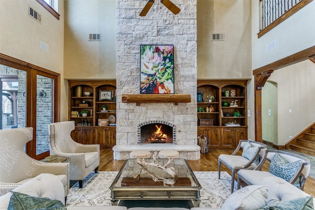 living area with visible vents, a stone fireplace, and wood finished floors