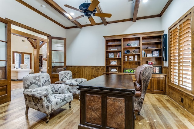 home office with lofted ceiling with beams, wooden walls, a ceiling fan, light wood-style floors, and wainscoting